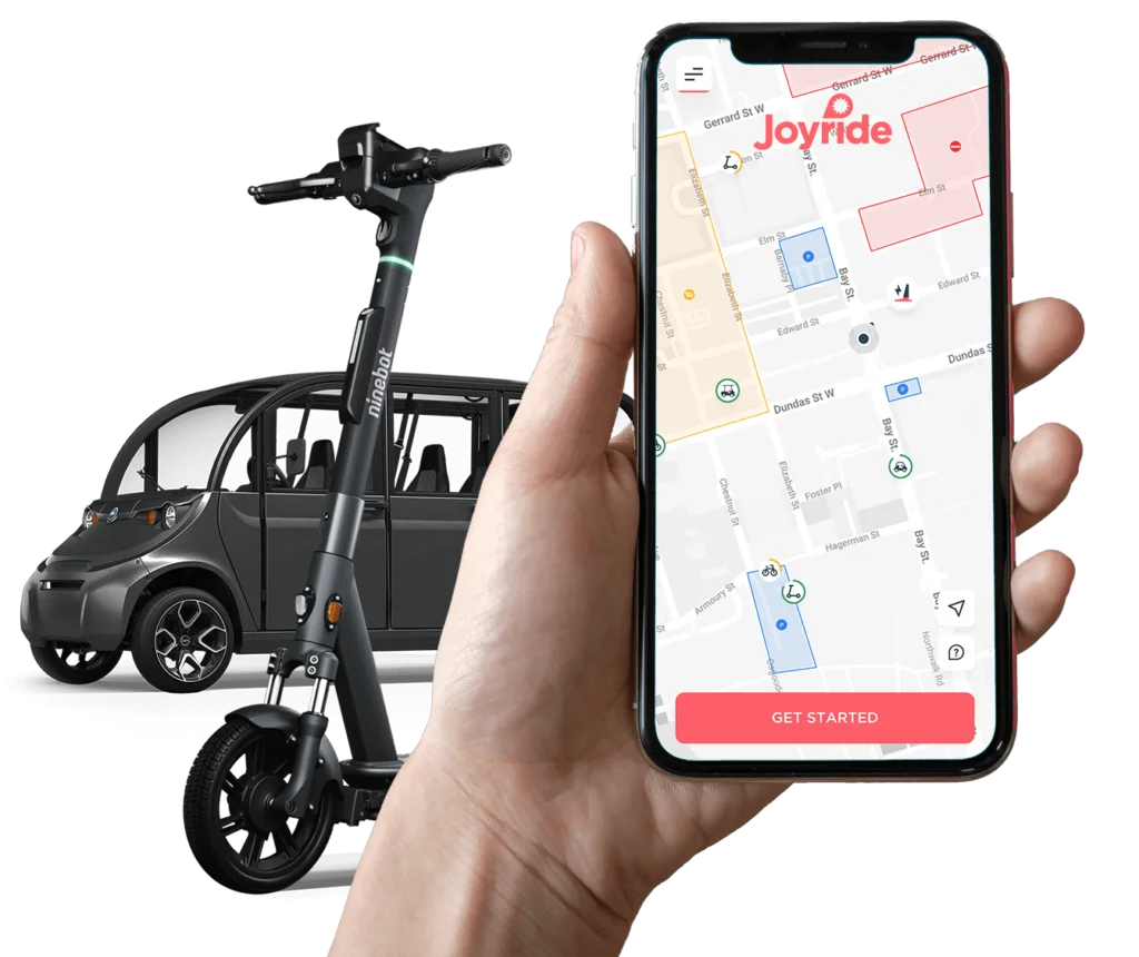 hand holding smartphone with Joyride vehicle sharing app in front of gem car and e-scooter
